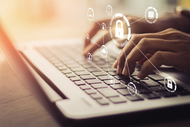Young businesswoman working on his laptop in the office, select the icon security on the virtual display.